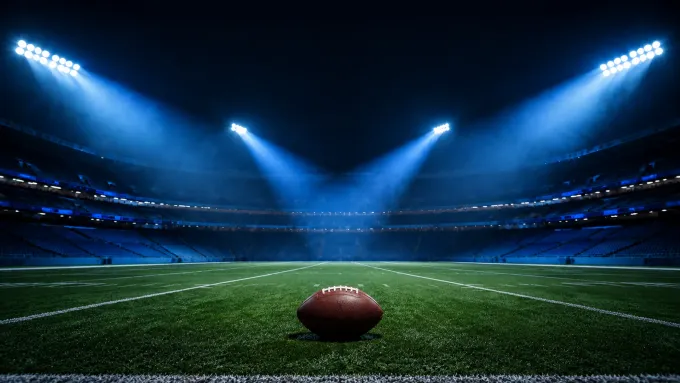 Original editorial illustration of one football on an empty field under four banks of blue stadium lights.